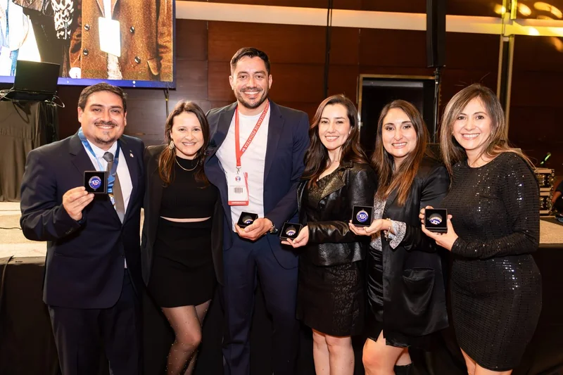 Grupo de asistentes posando con reconocimientos al cierre
