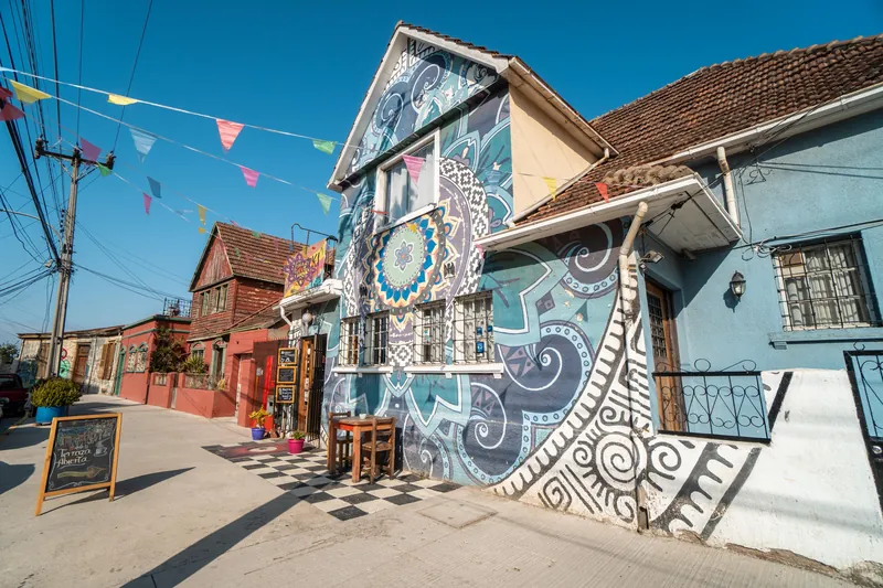 Fachada con mural colorido y banderines de un hostal